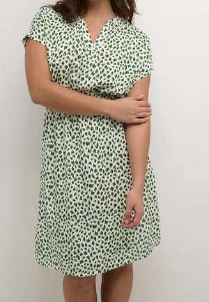 Short-sleeve dress in white fabric with green and blue leopard spots. Features a V-neck and gathered waist for a relaxed fit.
