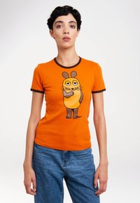 Orange cotton t-shirt with dark brown trim, featuring a cartoon character with round ears and whiskers printed on the front.
