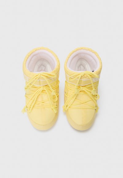 Yellow ankle boots made of soft, padded material with white inner lining. Features elastic laces and a round toe design.