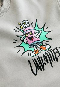 Szary sweatshirt z zabawnym graficznym wizerunkiem kreskówkowej postaci trzymającej napój, w żywych kolorach i odważnym napisie "NIEOGRANICZONE."