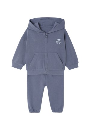 Gray zip-up hoodie and matching joggers made of soft cotton. Features front pockets and a circular logo with text on the upper left.
