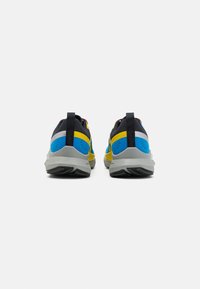 Scarpe sportive con tomaia nera, dettagli blu e gialli, suola grigia e retro testurizzato. Presentano linguette per una facile vestibilità.