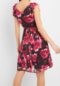 Kwiatowa sukienka z krótkimi, falbanistymi rękawami, na czarnym tle z dużymi różowymi wzorami róż. Związywany w pasie akcent i projekt z V w plecach.