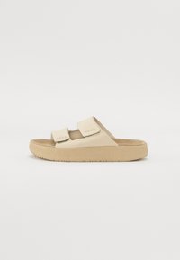Beiga slide-sandaler med två justerbara remmar, texturerad ovandel och gummisula med ribbat mönster. Varumärkeslogotyp präglad på remmen.