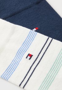 Heren sokken met marineblauw, wit en groen in horizontale strepen, een textuur gebreide stof en een detail met een rood, wit en blauw logo.