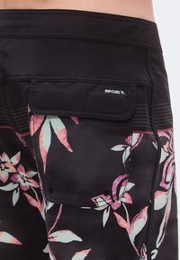 Mustad ujumispüksid roosade ja roheliste lillemustritega, taga tasku, logomärgise ning peente horisontaalsete triipudega.
