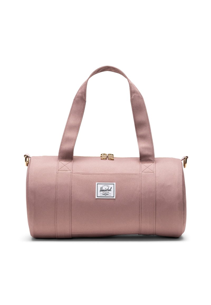 Pink cylindrical duffel bag with dual shoulder straps, gold zipper, and white Herschel brand logo patch on front center.