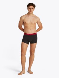 Mustad puuvillased bokserid, millel on lai punane "HILFIGER" logoga vöökoht. Üksus istub hästi ja sellel on keskmine tõus ning nähtavaid mustreid ei ole.