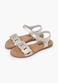 Metallic silver flat sandals with braided strap design, adjustable ankle strap, and textured beige footbed. Lightweight rubber sole.