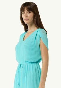 Jasnoniebieska, plisowana sukienka z dekoltem w kształcie litery V i krótkimi rękawami, z elastyczną talią i wiązaniem, wykonana z lekkiego materiału.