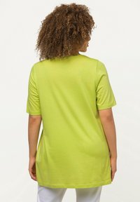 Limonengrünes Tunika-Oberteil mit kurzen Ärmeln aus weichem Jersey-Stoff, mit lockerer Passform und abgerundetem Saum, ohne sichtbare Muster oder Beschläge.