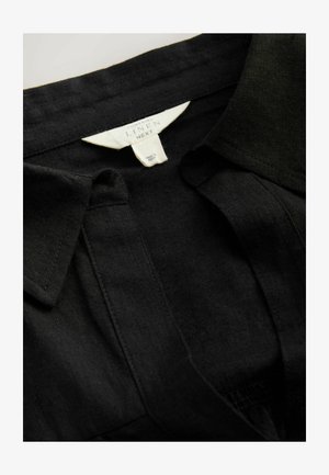 Melnas lina krekls ar klasisku apkakli, pogu svītru un smalku tekstūru, ar birku, kas norāda materiāla sastāvu.