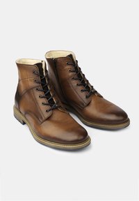 Botas de tobillo de cuero marrón con un acabado suave, diseño de cordones, cremallera lateral y un panel texturizado en el talón. Suela de goma.
