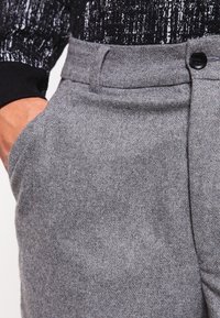 Szare wełniane spodnie o gładkiej fakturze, z pętlami na pasek, zapięciem na guzik oraz bocznymi kieszeniami i dopasowanym krojem.