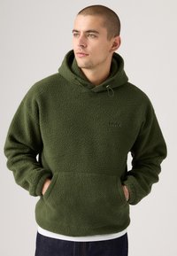 Green fleece hooded sweatshirt with a textured surface, kangaroo pocket, adjustable drawstring, and subtle logo on the front.