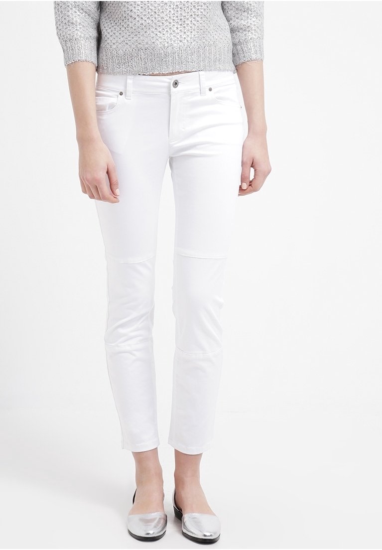 Jeans blancos ajustados con una textura suave, diseño de cinco bolsillos, cierre frontal con botón y detalles de costura sutiles. Combinados con zapatos planos plateados.