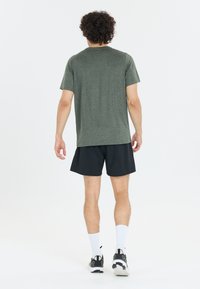 Camiseta gris de mangas cortas, combinada con pantalones cortos negros. La tela parece ligera, adecuada para uso casual o deportivo.