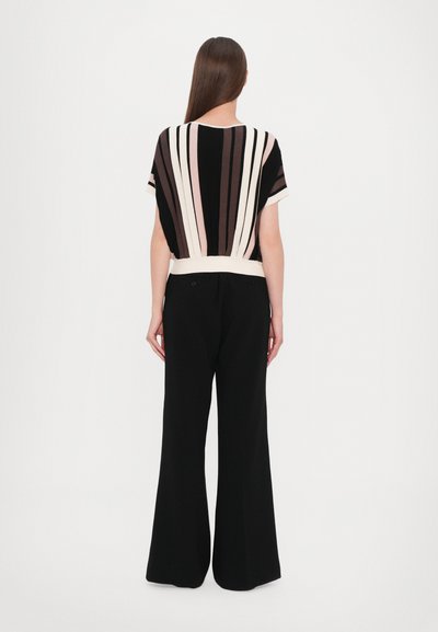 Black and cream striped top with short sleeves, paired with high-waisted black wide-leg pants. Smooth fabric with a relaxed fit.