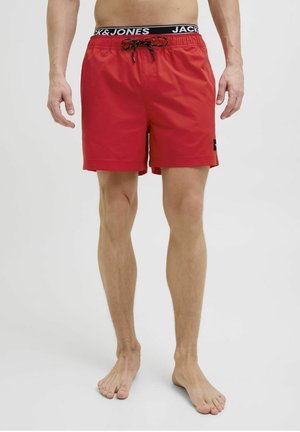 Rode zwemshorts van lichtgewicht stof, met een elastische tailleband en een zwarte trekkoord, en een logo patch aan de zijkant.