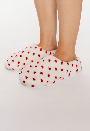 Pantofole bianche morbide con motivo a cuore rosso, punta arrotondata, texture soffice, design slip-on senza elementi o accenti visibili.