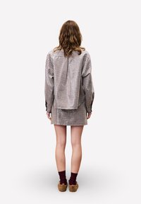 Kurzärmliges Oberteil im karierter Muster und passende karierte Shorts in Erdtönen. Weicher Stoff, entspannte Passform, kombiniert mit burgunderfarbenen Socken und braunem Schuhwerk.