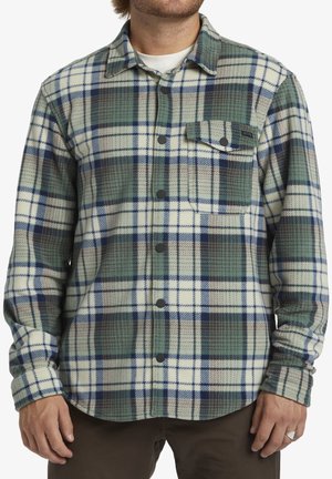 Camisa de franela con un patrón a cuadros en verde, azul y crema. Presenta un diseño de botones, un bolsillo en el pecho y una textura suave.