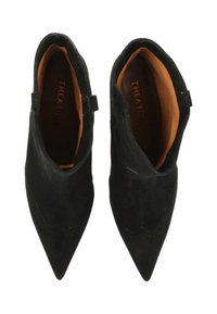 Black suede ankle boots featuring a pointed toe, scalloped design at the front, and a brown inner lining. Two small loop accents at the heel.