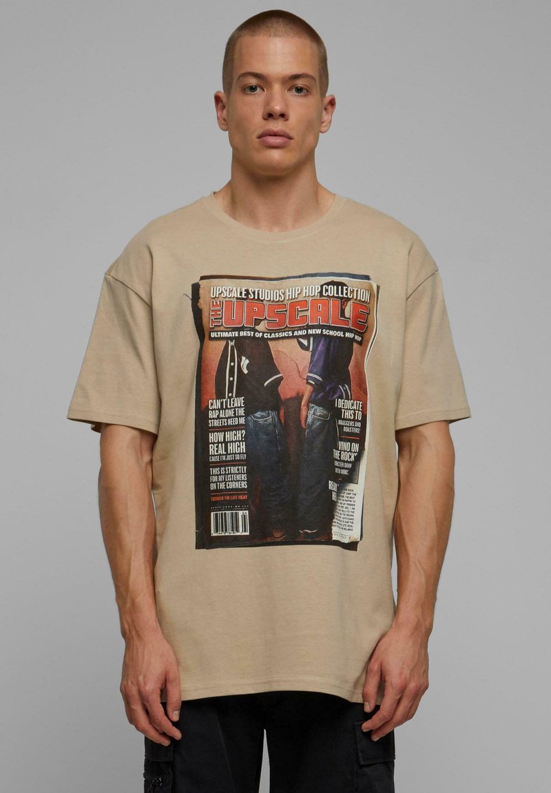 Beige oversize tričko vyrobené z bavlny, s potlačou dizajnu obálky časopisu so silným textom a obrázkami. Krátke rukávy a okrúhly výstrih.