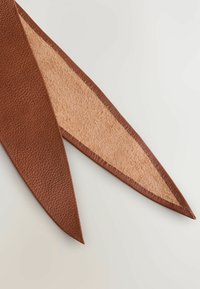 Brun läder dekorativ accent med en texturerad yta, tillsammans med en slät beige inredning. Avlång, spetsig form för designmångsidighet.