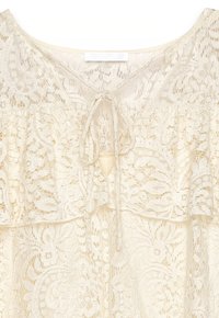 Spitzenoberteil in Creme mit floralen Mustern, V-Ausschnitt, Rüschentier und einer Bindung am Ausschnitt. Leichter und strukturierter Stoff.