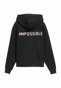 Zwarte hoodie met lange mouwen. Bevat grote witte en roze tekst "IMPOSSIBLE" over de rug. Stof lijkt zacht en gestructureerd.