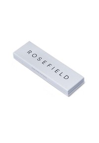 Boîte à bijoux rectangulaire blanche de la marque Rosefield avec un texte de logo noir et un petit slogan "Détails simples. Luxe pur." sur le côté.