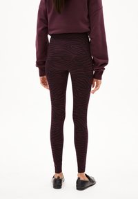 Paars en zwart zebra-gepatenteerde leggings met een hoge taille, gemaakt van rekbaar materiaal. G gedragen met zwarte instappers.