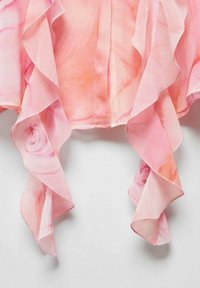 Top in chiffon rosa con maniche a volant, caratterizzato da un morbido motivo floreale e leggera texture, che si adagia elegantemente sul colletto.
