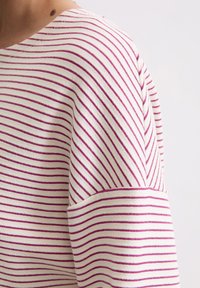Gestreiftes Strickoberteil mit weißen und fuchsiafarbenen horizontalen Linien, rundem Halsausschnitt und kurzen Ärmeln in lockerer Passform.