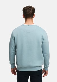 Ljusblå sweatshirt i mjukt tyg. Har rund hals, långa ärmar samt ribbad mudd vid ärmslut och fåll. Enfärgad, utan mönster.