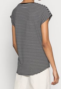 Camiseta de rayas blancas y negras con mangas cortas, escote redondo y dobladillo ligeramente curvado. Fabricada en una tela suave y ligera.