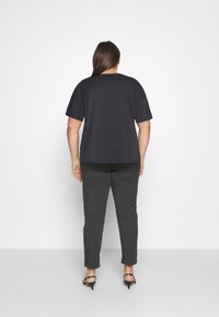 Sort kortærmet t-shirt med en afslappet pasform, parret med mørkegrå, tapered bukser, der har en blød tekstur og ankel-længde kant.