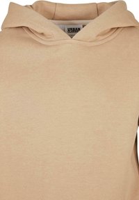 Sudadera beige con capucha de doble capa y etiqueta interior visible etiquetada "Urban Classics" en tamaño 122/128.