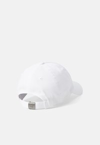 White cotton baseball cap with a curved visor, adjustable strap at the back, and a silver metal tag embossed with "Golf."