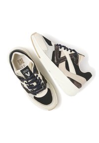 Sportliche Sneaker aus einer Kombination von schwarzem Netzmaterial, cremefarbener Leder und metallischen Akzenten. Die dicke weiße Sohle und die marineblauen Schnürsenkel ergänzen das Design.