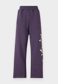 Lilla joggebukser med elastisk midje, sidelommer og et gullfarget grafisk design på venstre bein. Mykt materiale med løs passform.