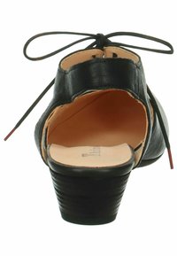 Scarpa nera in pelle con tacco, punta rotonda, apertura sul retro e dettagli in pizzo nella parte superiore. Tacco testurizzato con un interno liscio.