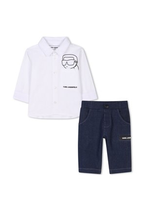 Camicia bianca a maniche lunghe con una grafica di cartone animato nera e logo, abbinata a pantaloni in denim scuro con un patch logo e tasche strutturate.