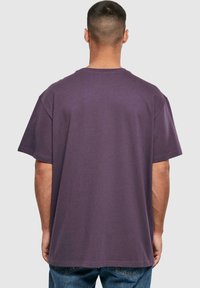 Lilla oversized t-shirt med korte ærmer, rund hals og ribbet tekstur. Har en lige kant og en afslappet pasform.
