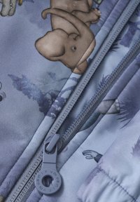 Tissu bleu clair avec des illustrations d'animaux, muni d'une fermeture éclair grise et d'un tirette. Les textures notables incluent une finition lisse et des éléments rembourrés.