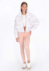 White puffer jacket with a marble pattern, cropped design, worn over a white crop top, paired with light pink leggings and white sneakers.