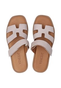 Lichtbeige slide-sandalen met een brede strap met een uitgesneden ontwerp. Gestructureerde bruine zool met een gladde binnenvoering.