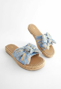 Sandales à glissière en tissu tissé bleu et beige avec un détail de nœud, semelle en corde naturelle, forme arrondie et semelle plate.