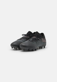 Scarpe da calcio nere con tomaia in materiale sintetico testurizzato, chiusura con lacci e accenti rosa. Presentano un collare simile a una calza e tacchetti moldati per una migliore trazione.